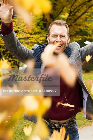Man playing in autumn leaves