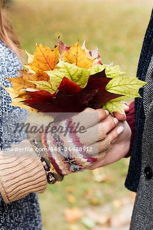 Close up of couple holding autumn leaves