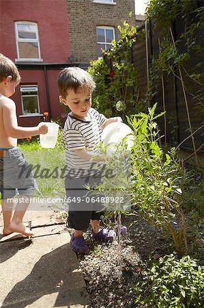Boys watering plants in garden