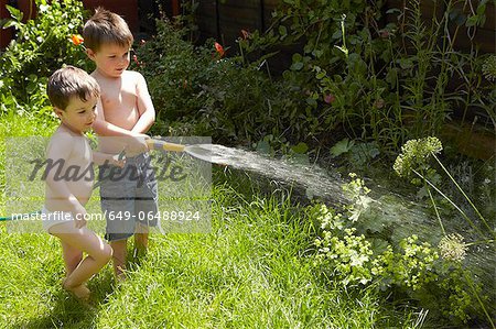 Boys watering plants in garden