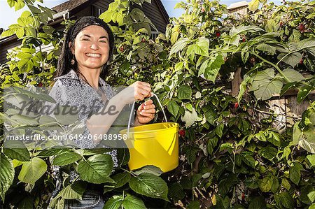 Smiling woman picking fruit in garden