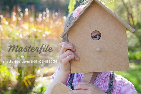 Girl peeking through birdhouse