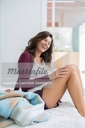 Smiling woman sitting on bed Smiling woman sitting on bed
