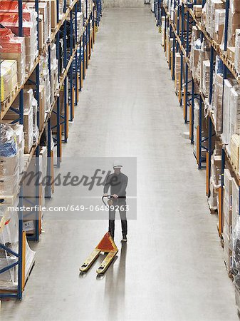 Worker operating dolly in warehouse