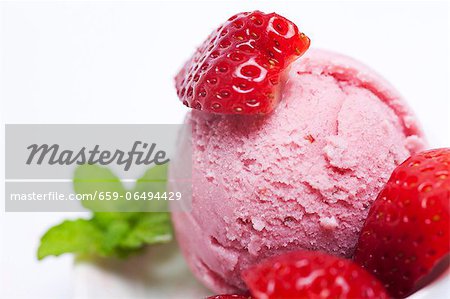 A scoop of fresh strawberry ice cream with fresh strawberries