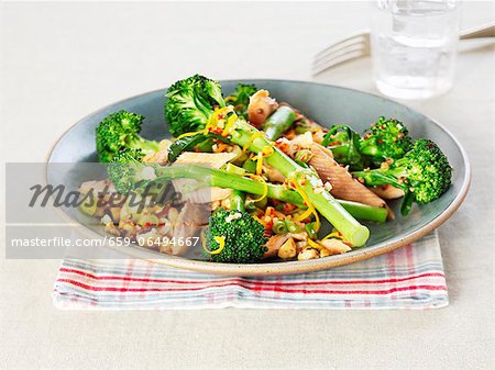 A plate of salmon with broccoli, nuts and orange zest