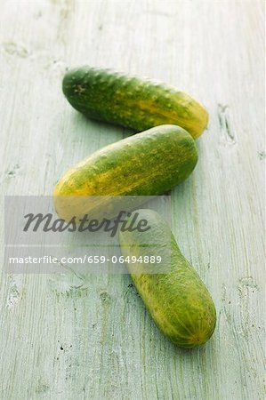 Three gherkins on a wooden surface