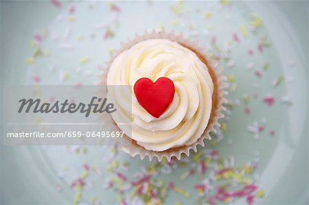 A cupcake decorated with light frosting and a red marzipan heart A cupcake decorated with light frosting and a red marzipan heart