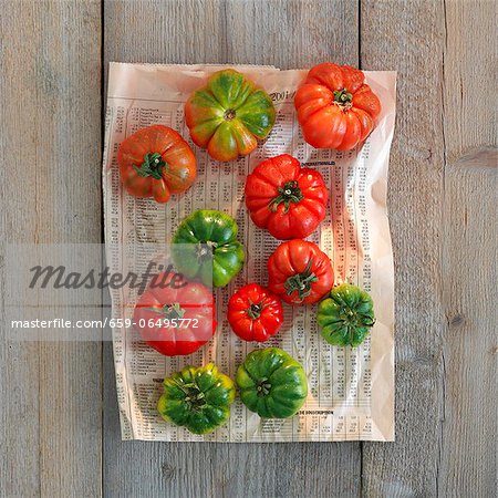 Green and red tomatoes on newspaper