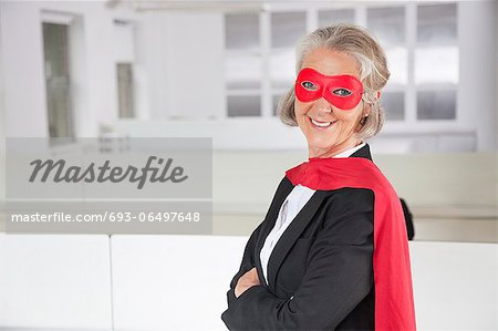 Portrait of smiling senior businesswoman in superhero costume in office