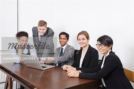 Portrait of multiethnic professionals using laptop at conference room