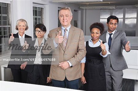 Portrait of multiethnic business group gesturing thumbs up at office