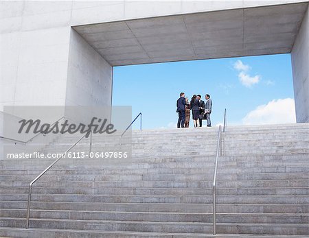 Business people meeting at top of urban stairs Business people meeting at top of urban stairs