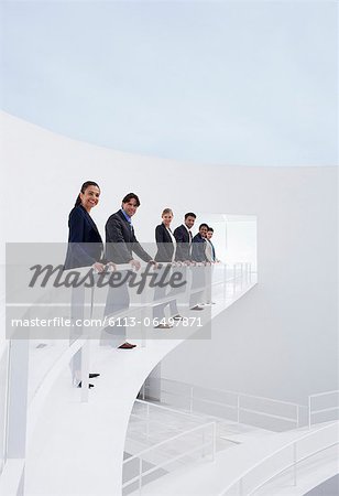 Portrait of smiling business people leaning on railing of elevated walkway