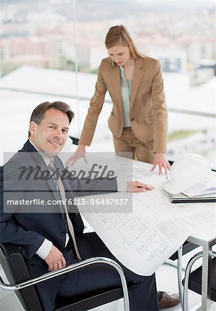 Portrait of confident architect reviewing blueprints with co-worker