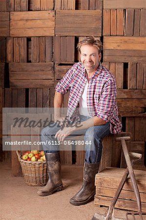 Portrait of smiling man sitting next to bushel of apples