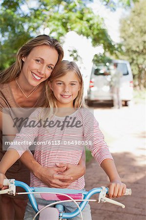 Portrait of smiling mother hugging daughter on bicycle