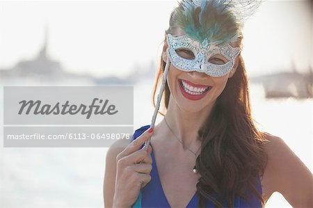 Portrait of smiling woman wearing mask at waterfront in Venice