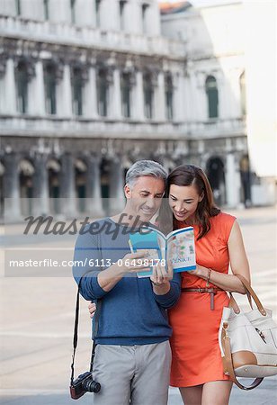 Smiling couple looking at guidebook in St. Mark's Square in Venice