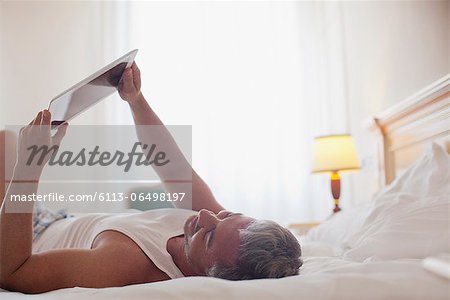Man laying in bed and using digital tablet