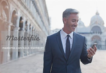 Smiling businessman checking cell phone in St. Mark's Square in Venice