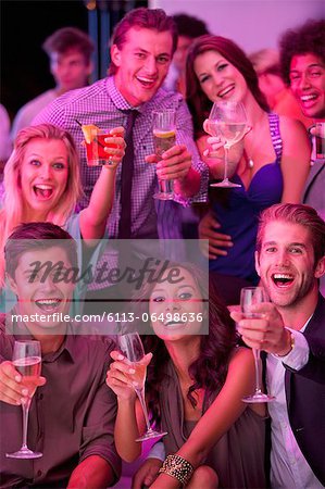 Portrait of smiling friends drinking cocktails in nightclub