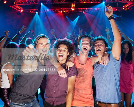 Enthusiastic friends cheering on dance floor of nightclub