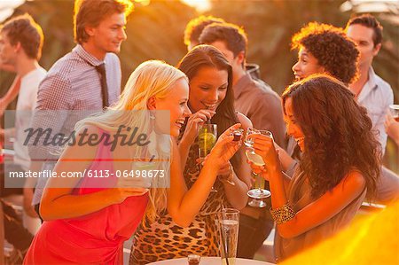 Smiling women drinking cocktails on sunny balcony