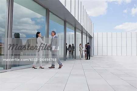 Businessman and businesswoman shaking hands outside building