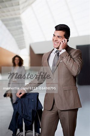 Smiling businessman talking on cell phone at airport