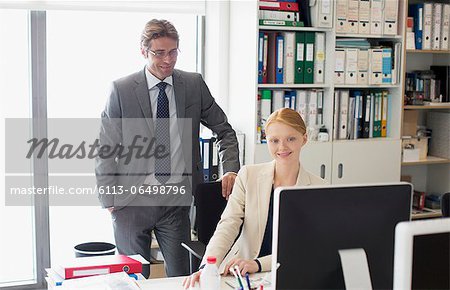 Businessman and businesswoman using computer at desk in office