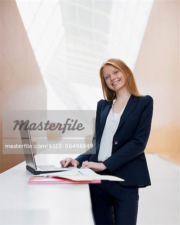 Portrait of smiling businesswoman using laptop in office