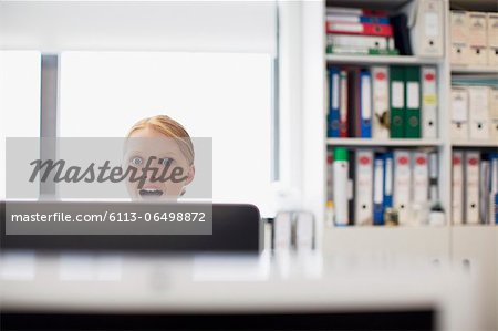 Surprised businesswoman reading e-mail at computer in office