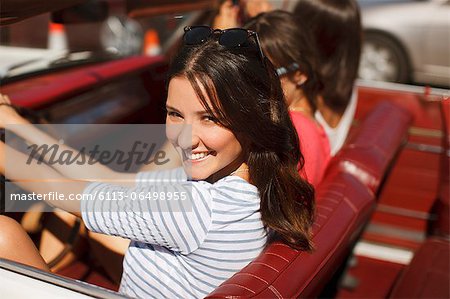 Smiling women driving convertible