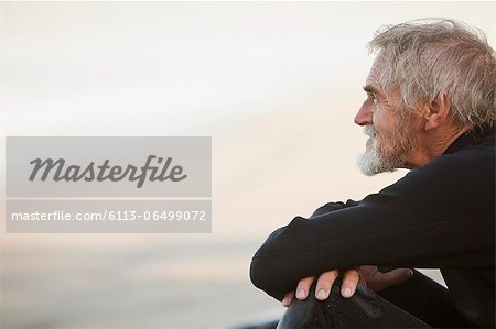 Older surfer sitting on beach