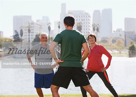 Older couple exercising with trainer in park