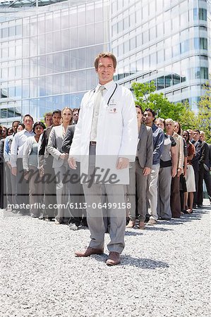 Portrait of smiling doctor with business people in background