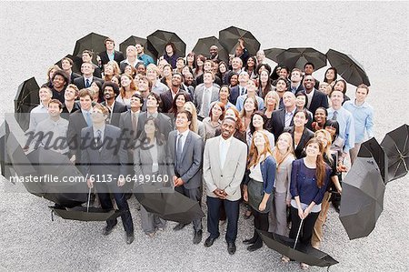 Portrait of smiling business people with umbrellas looking up