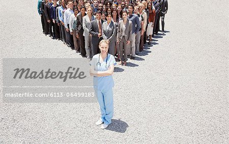 Portrait of confident nurse with business people in background
