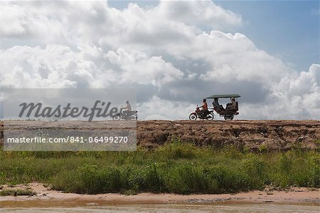 A motorbike being followed by a moto-rickshaw along the banks of the Tonle Sap Lake, Cambodia, Indochina, Southeast Asia, Asia