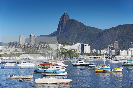 Boats moored in harbour with Christ the Redeemer statue in background, Urca, Rio de Janeiro, Brazil, South America