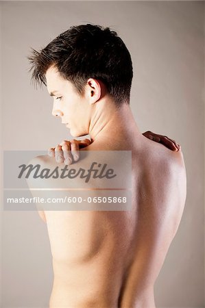 Close-up, Backview of Young Man Rubbing Shoulders with Hands, Studio Shot Close-up, Backview of Young Man Rubbing Shoulders with Hands, Studio Shot