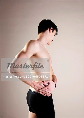 Side View of Young Man wearing Underwear and Holding Hip with Hands, Studio Shot Side View of Young Man wearing Underwear and Holding Hip with Hands, Studio Shot