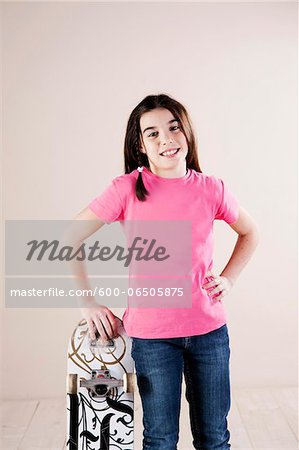 Portrait of Girl Standing and Leaning on Skateboard, Smiling at Camera, Studio Shot