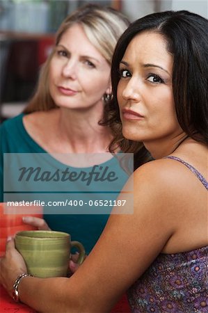 Concerned Hispanic and Caucasian ladies sitting in restaurant