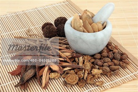 Chinese herbal medicine selection in a marble mortar with pestle and loose over bamboo mats.