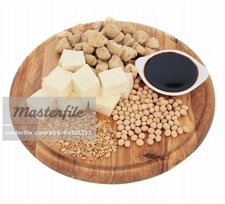Soybean products of flakes, chunks, beans, sauce and tofu on a wooden board isolated over white background.