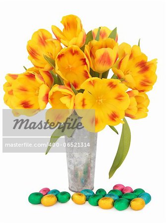 Chocolate easter egg group with red and yellow striped tulip flower arrangement in an aluminium vase over white background.