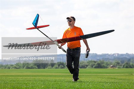 Man holds the RC glider, on grass field