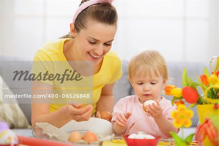 Happy mother and baby eating Easter eggs